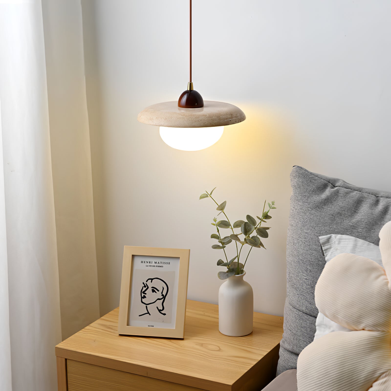 Stone bedside pendant beside cushions and a small vase