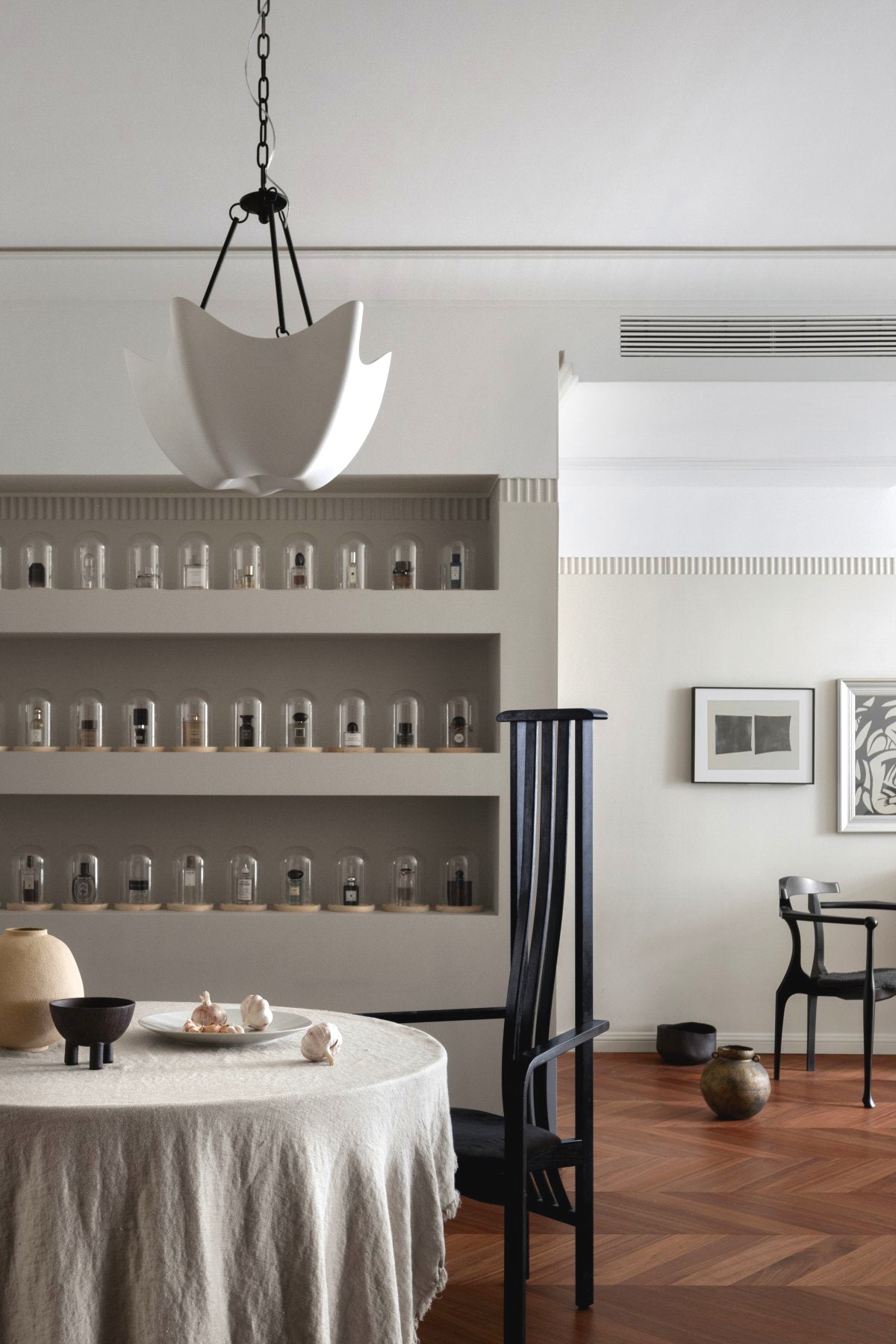 Antique Black Cosima chandelier above a table near display shelves