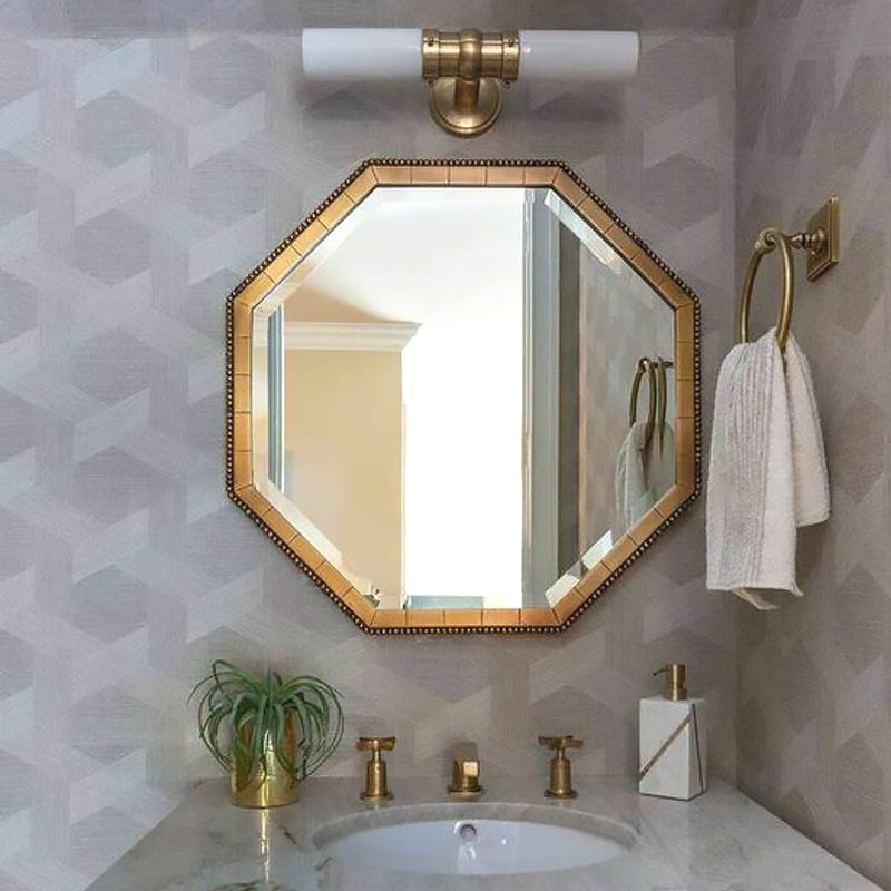 Horizontal brass-tone double white-glass wall light above an octagonal gold-framed mirror on a grey wall