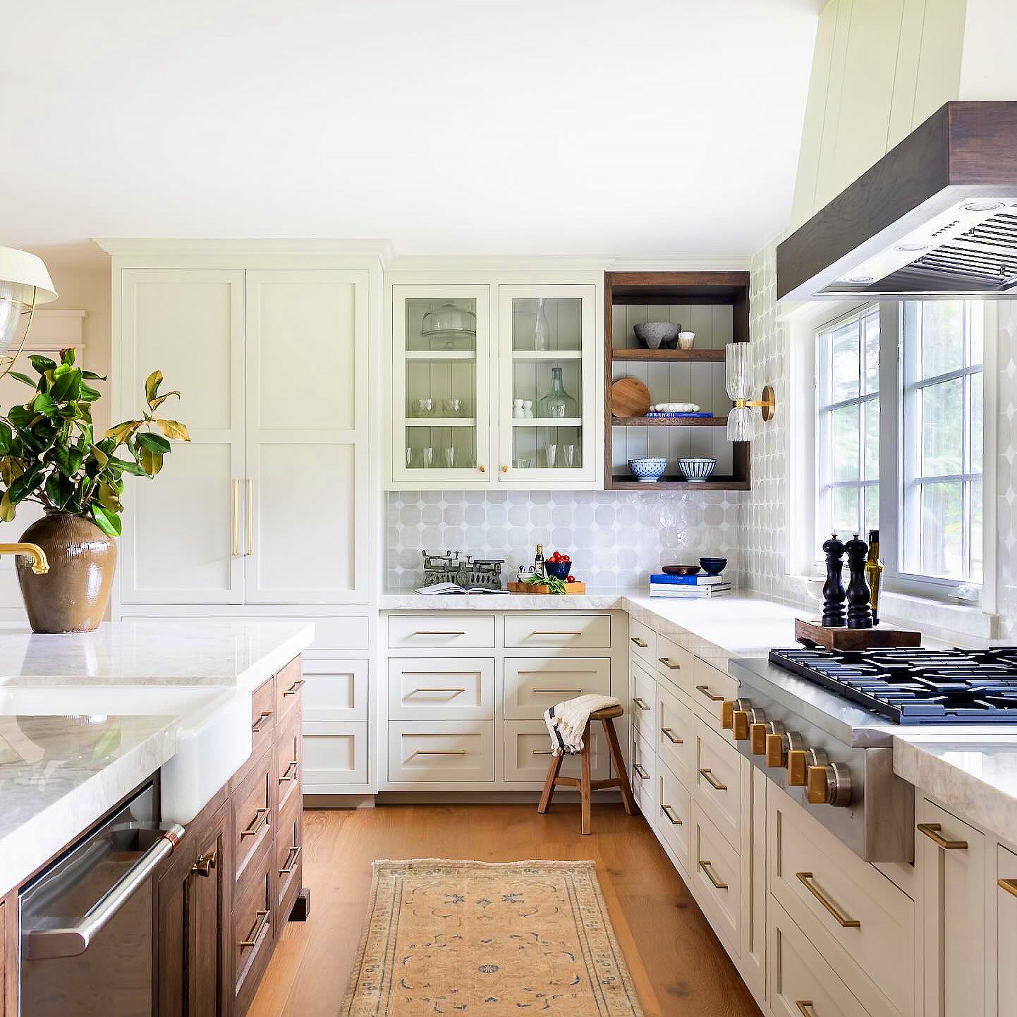 Single Antique Brass-tone double glass sconce by a large kitchen window with cream cabinets and plants