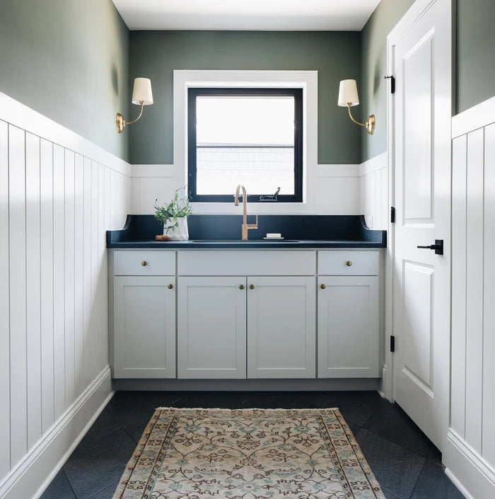 Single-shade wall lights flanking a window over a compact vanity.