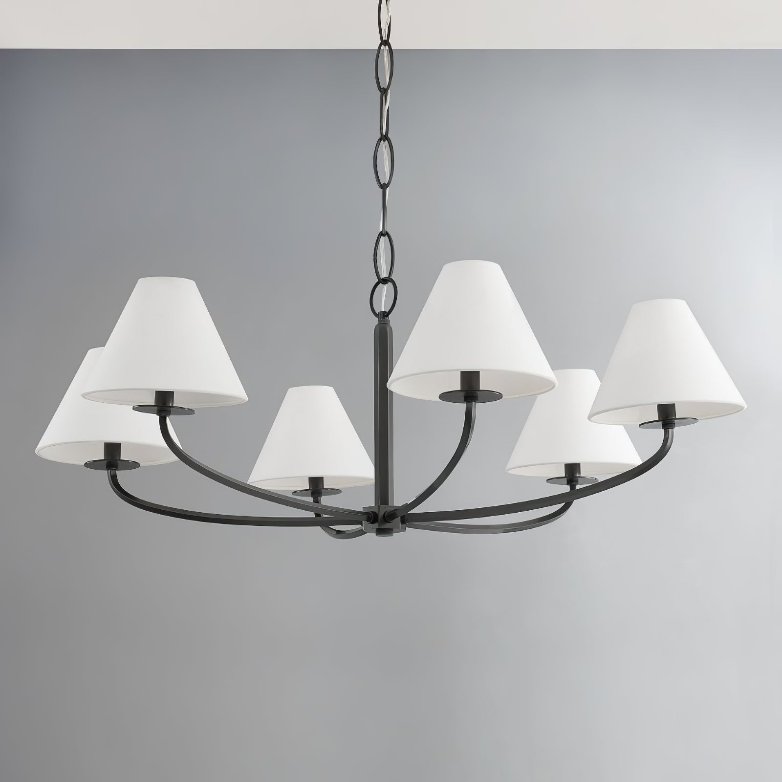 Close view of six-light Black Stacey curved arms, white shades, central hub and chain against grey