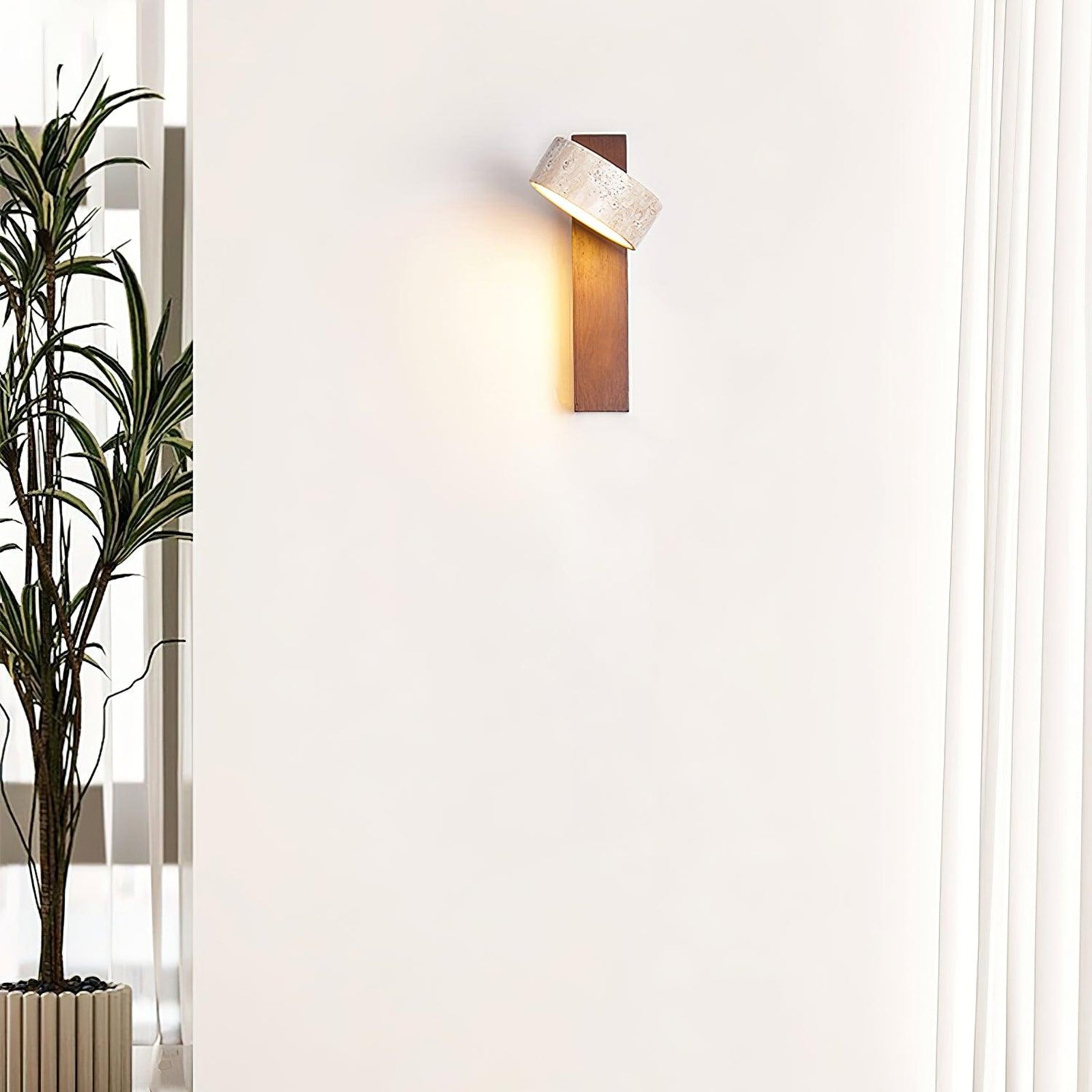 Walnut-colour stone wall lamp with angled shade beside a plant