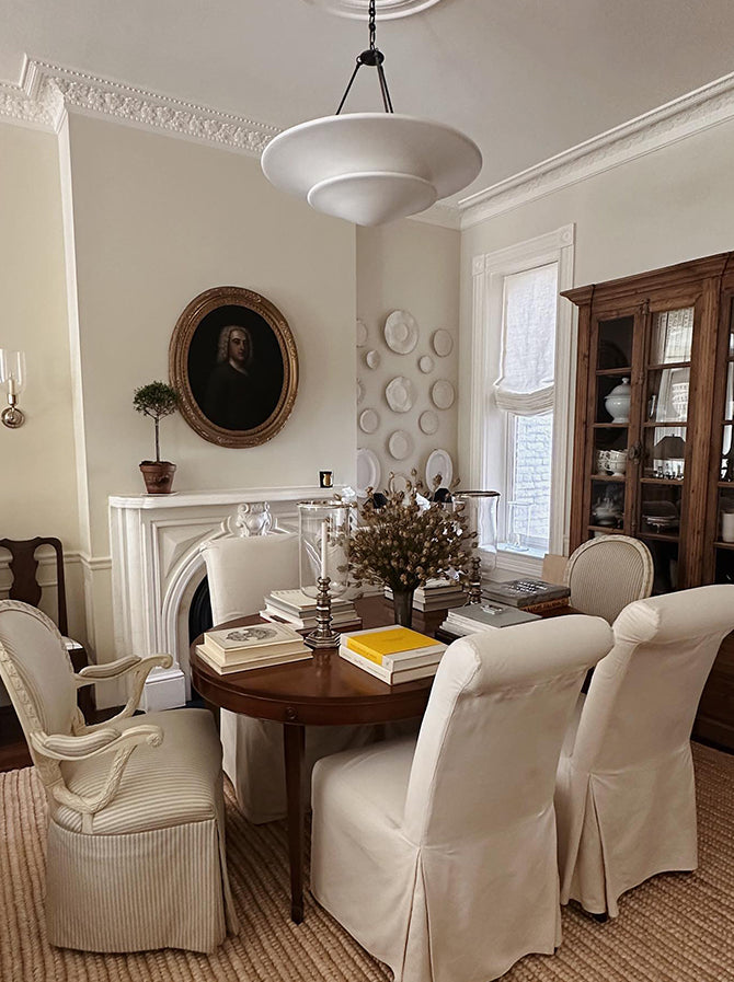 Mollino white bowls with black supports and chain above round table in ornate dining room with books and candles