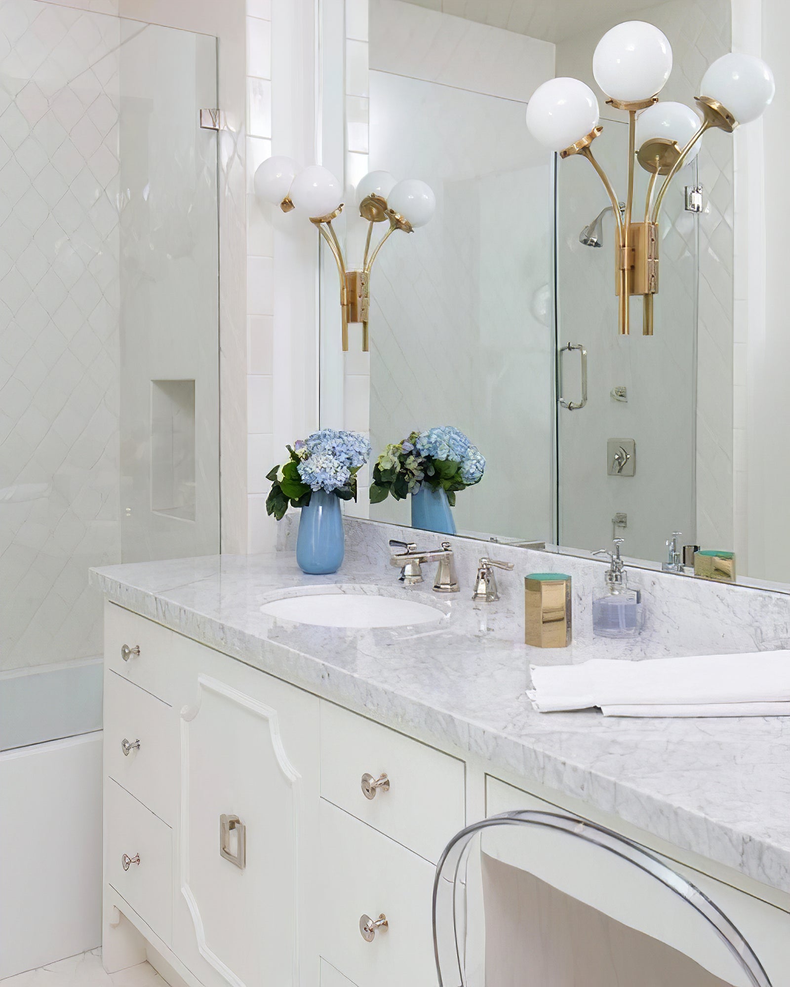 Brass white-glass sconces beside a mirrored vanity