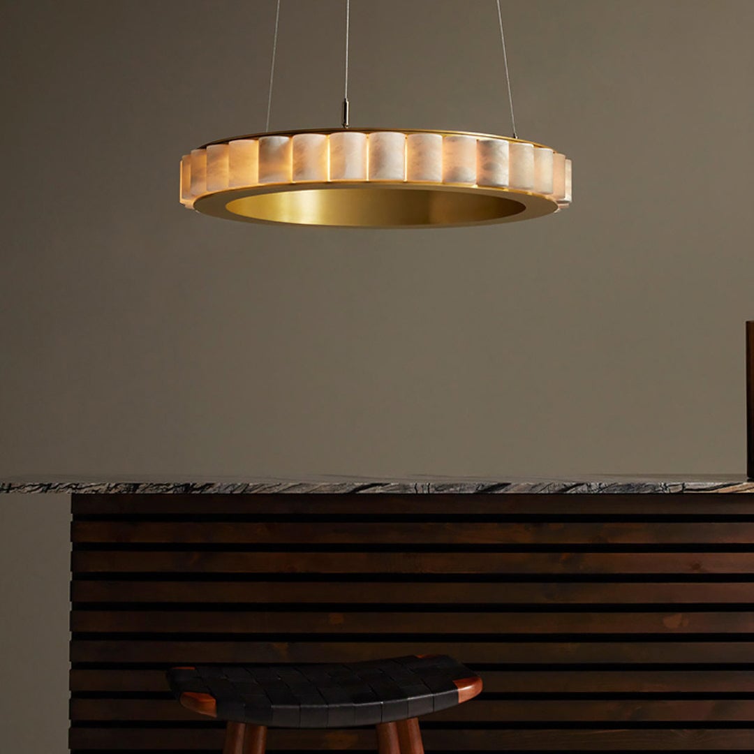Single gold-tone-band segmented ring above a dark slatted counter and stool