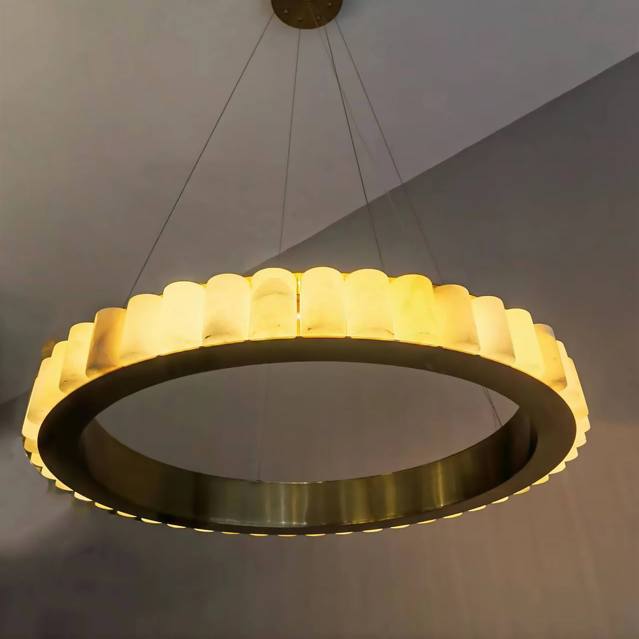 Close underside of a gold-tone ring with pale veined segments and thin suspension cables