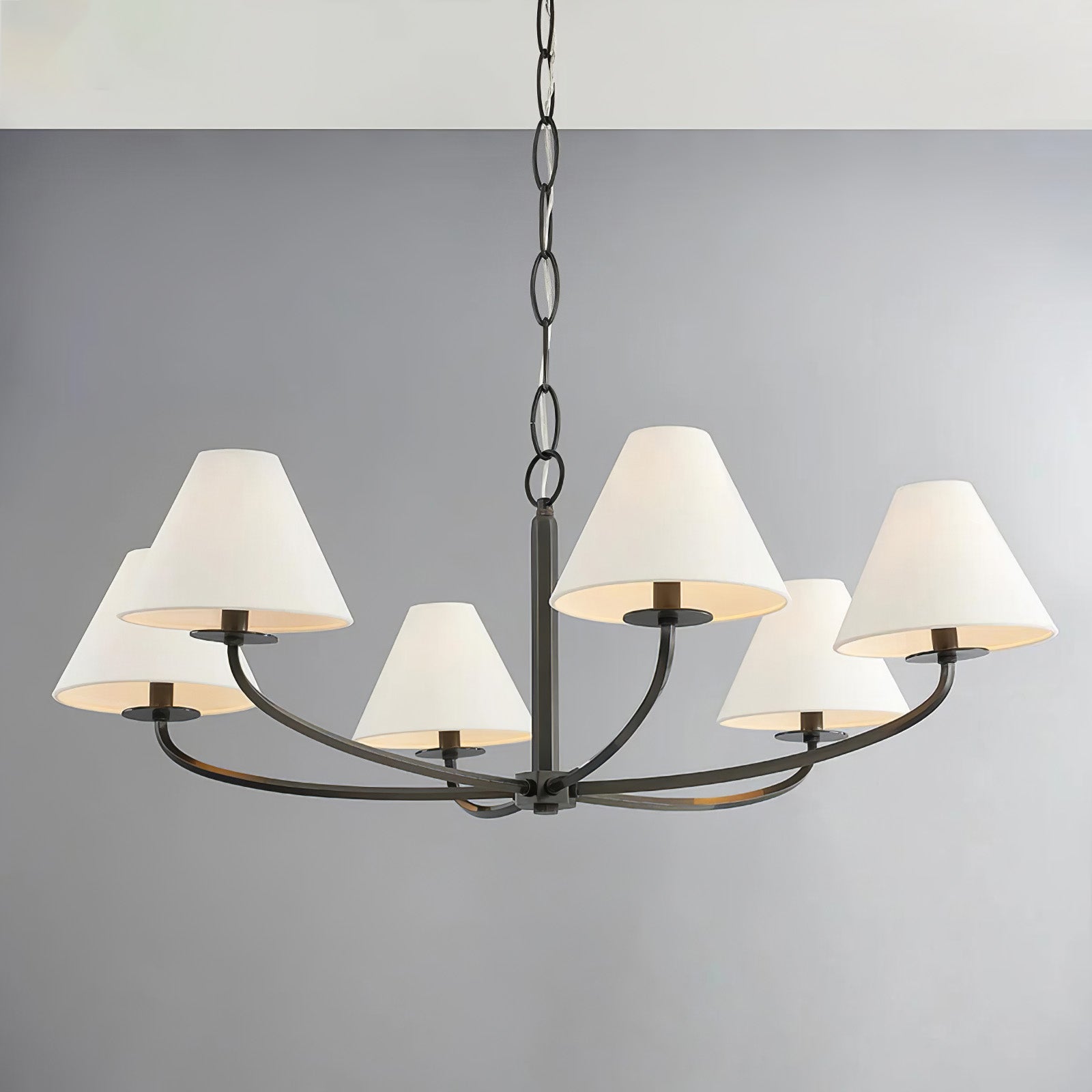 Six-light Black Stacey chandelier with softly glowing white fabric shades, curved arms and chain against grey