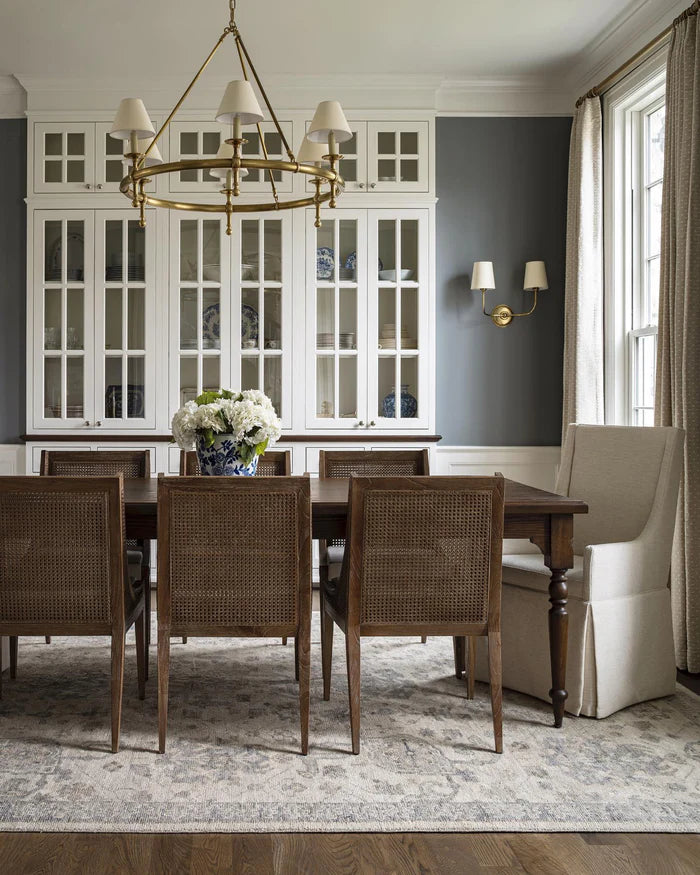 Small shaded wall lights in a dining room with a large chandelier.