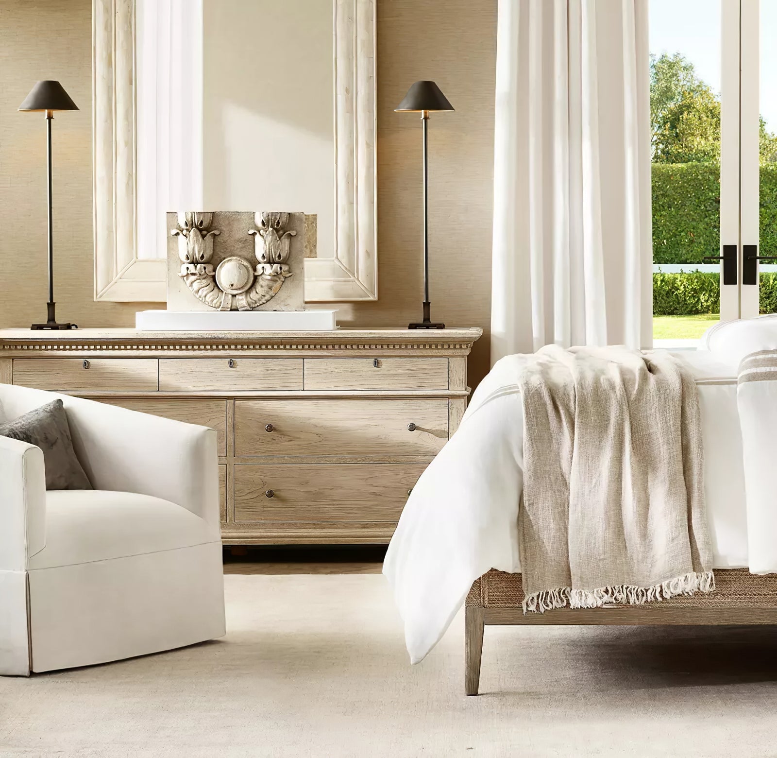 Two dark-shade Slim Candlestick lamps on wooden chest below white-framed mirror beside bed and upholstered chair