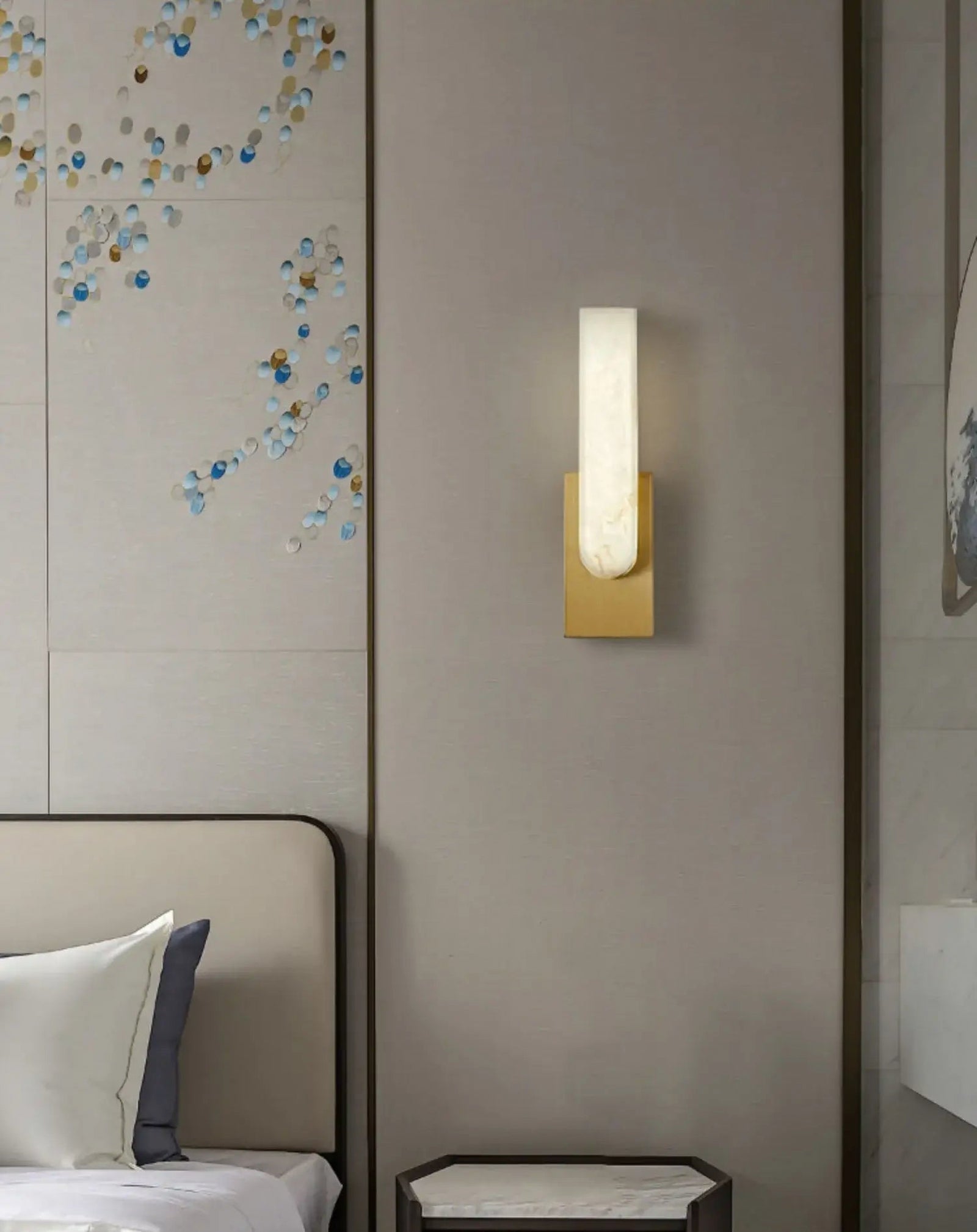 Gold sconce beside a bed and framed wall art