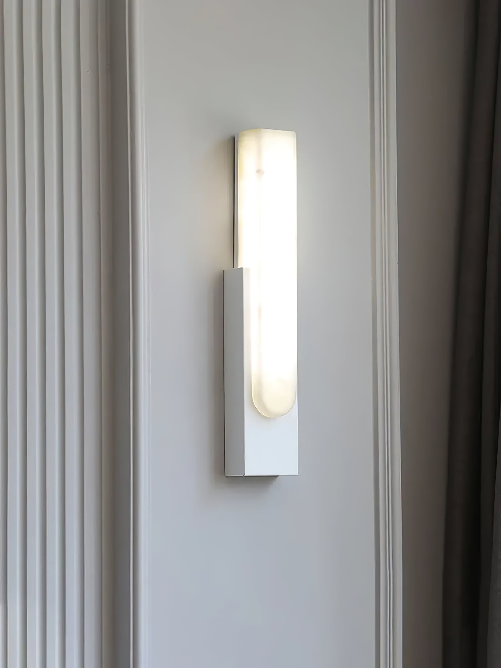 White wall sconce against paneled wall