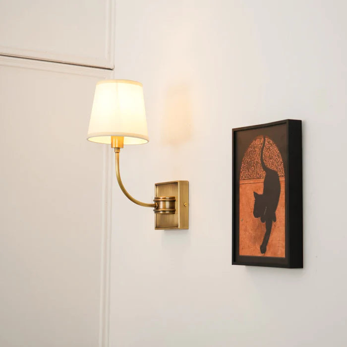 Square-backplate brass single lamp beside a small framed portrait.