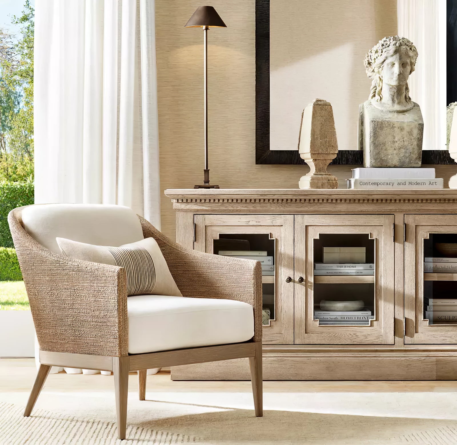 Dark-shade Slim Candlestick lamp on wood cabinet beside upholstered armchair and stone bust near window