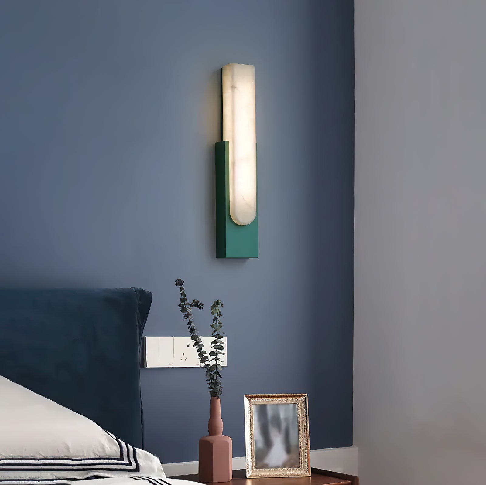 Green wall sconce beside a bed