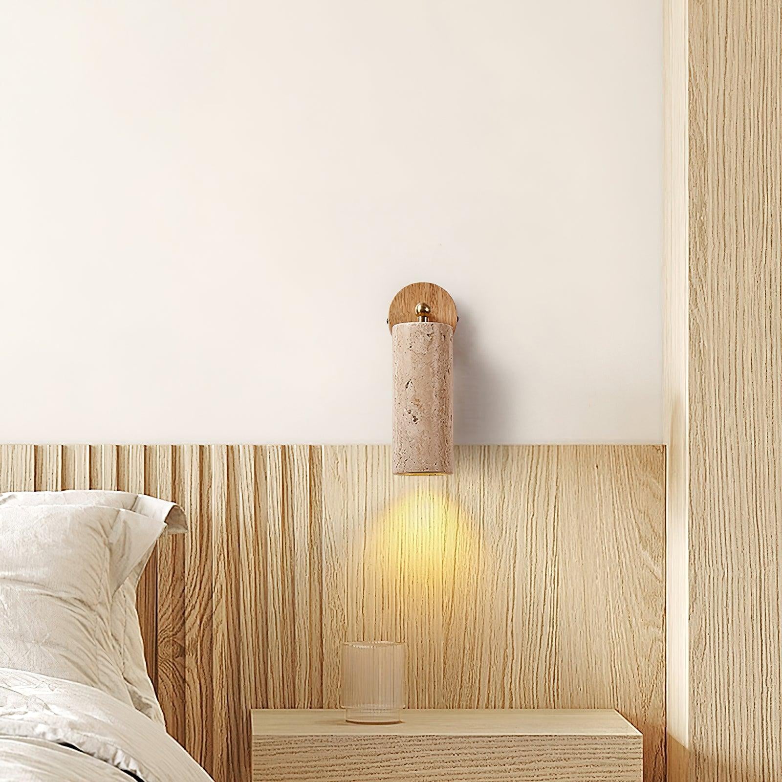Mireille stone cylinder wall lamp casting light over a bedside cabinet
