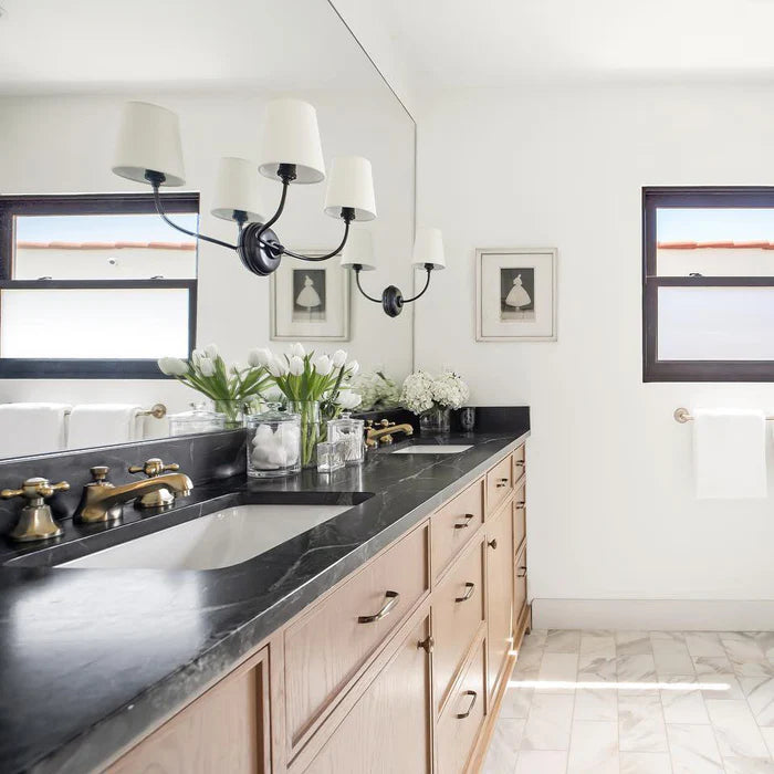 Black three-shade wall lighting above a double vanity and mirror.