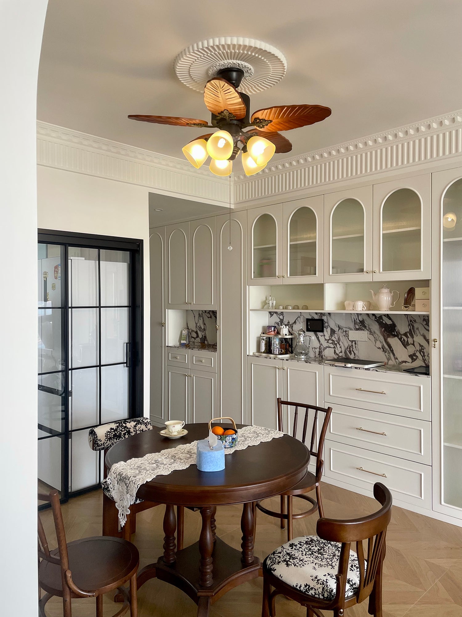Leaf-pattern fan with five lights above a dining table