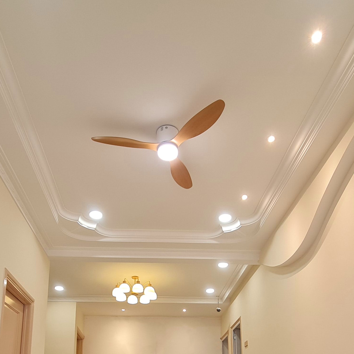 Wood-toned fan beneath a bright ceiling with spotlights
