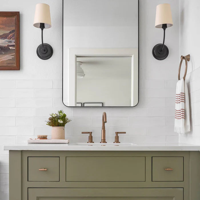Two black single wall lights beside a rounded-corner vanity mirror.