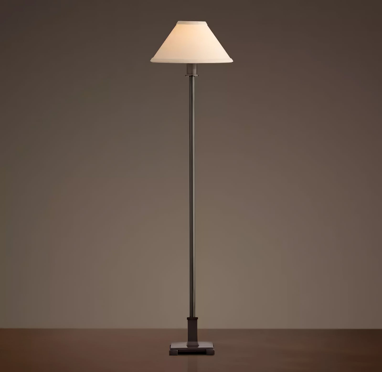 Grey-toned Slim Candlestick lamp with illuminated light conical shade, straight stem and stepped base on dark tabletop