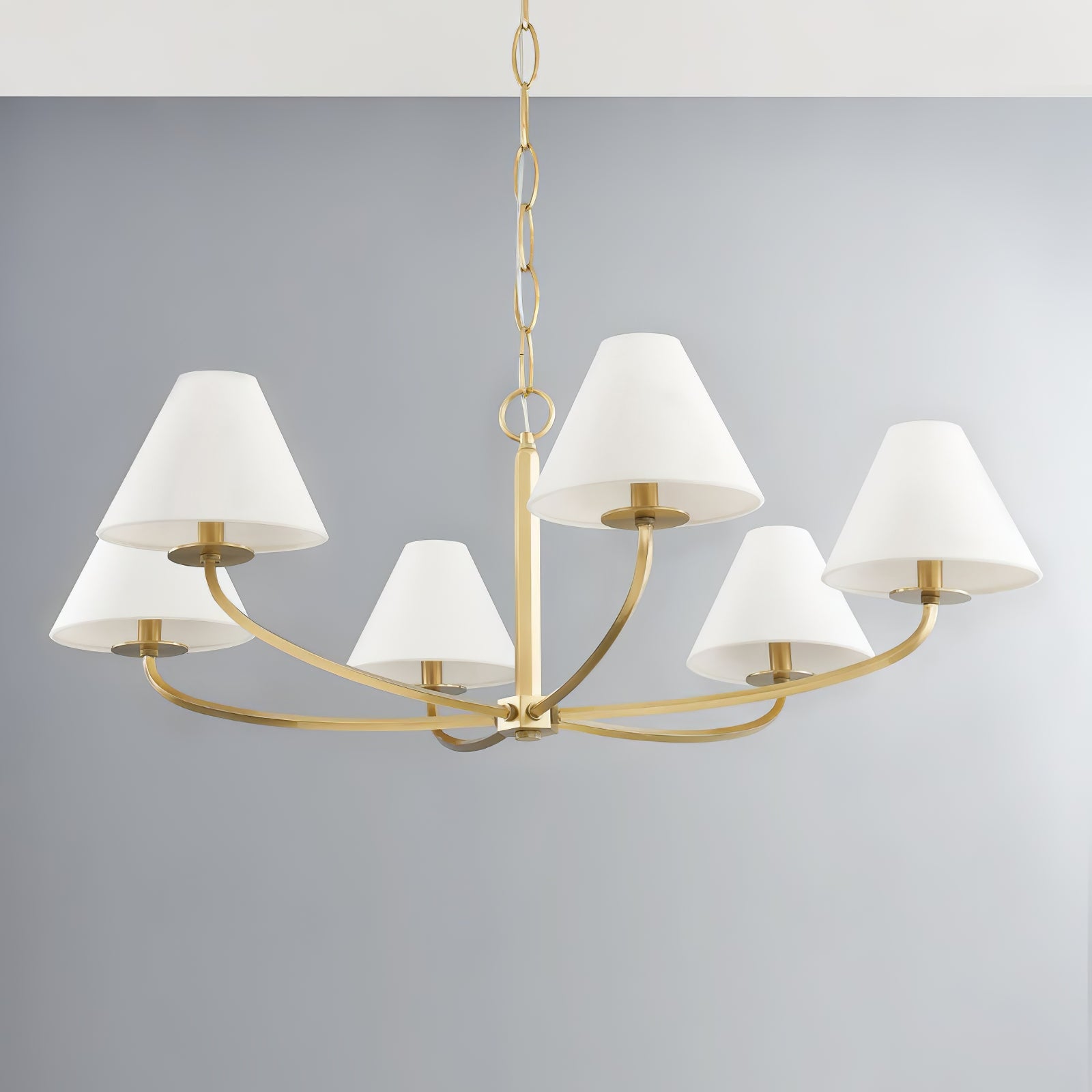 Six-light Bronze Stacey chandelier with gold-tone curved arms and chain, white fabric shades against grey