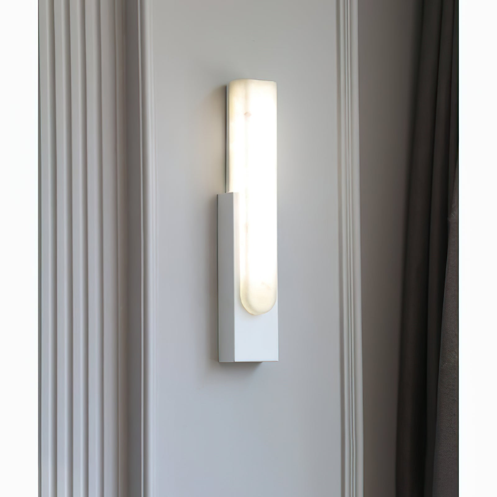 White vertical sconce beside a curtain