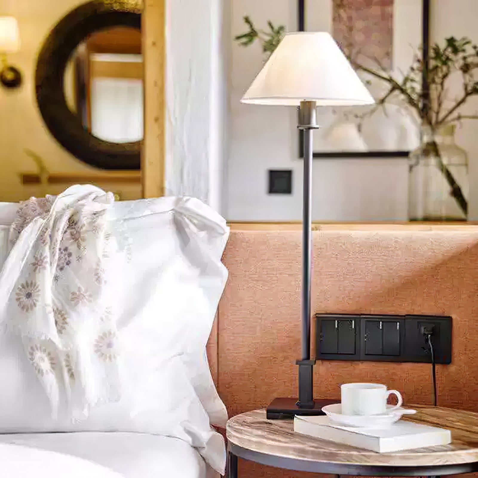 Black A Slim Candlestick lamp with light conical shade on bedside table beside white bedding, cup and book