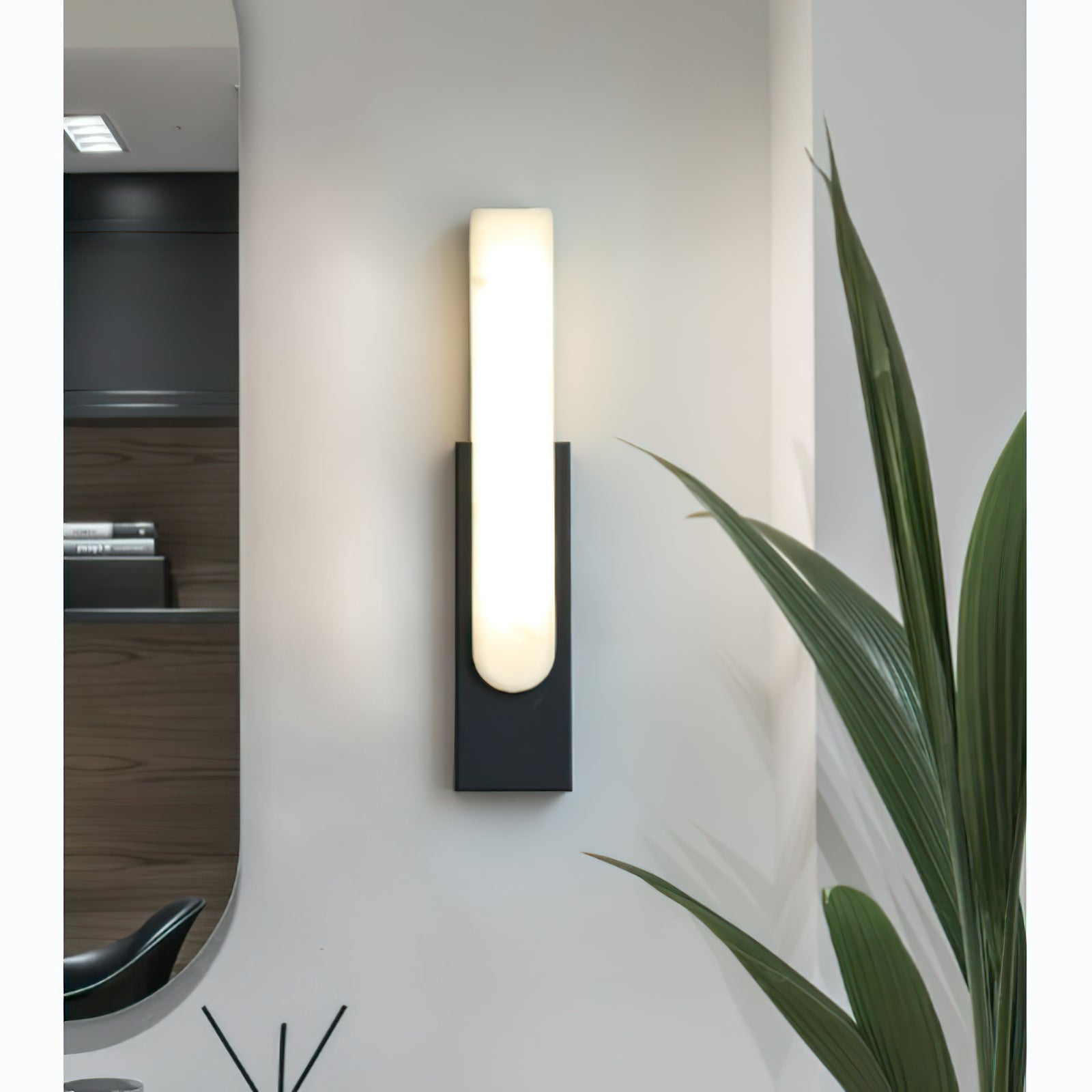 Black wall light above green plant