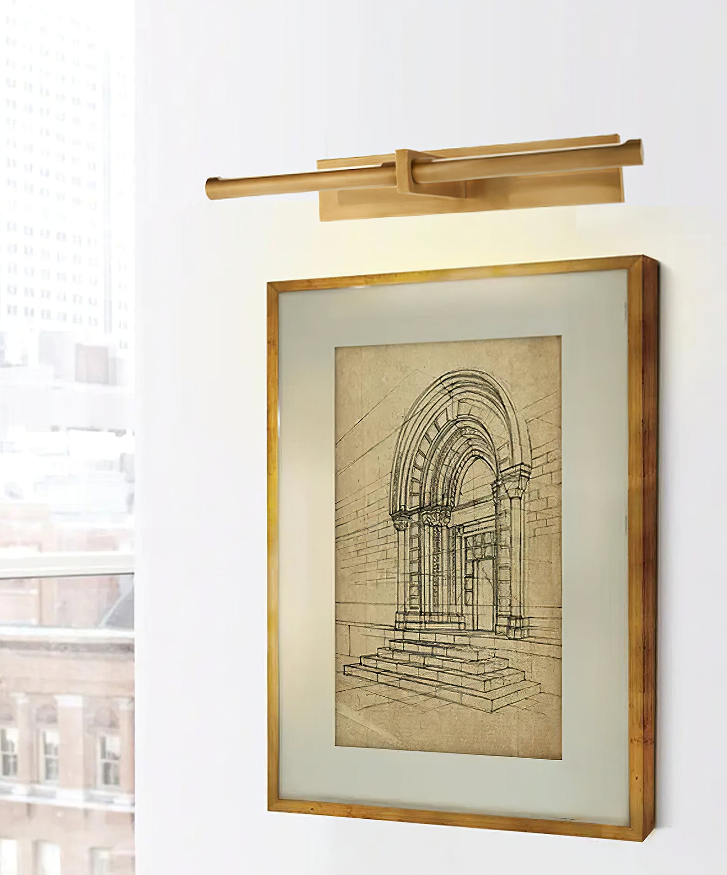 Brass-colour picture light above a framed architectural drawing beside a large window