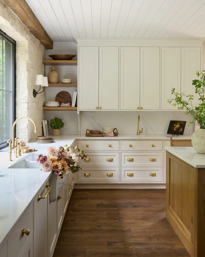 Brass single-shade lights beside kitchen windows and above a sink.
