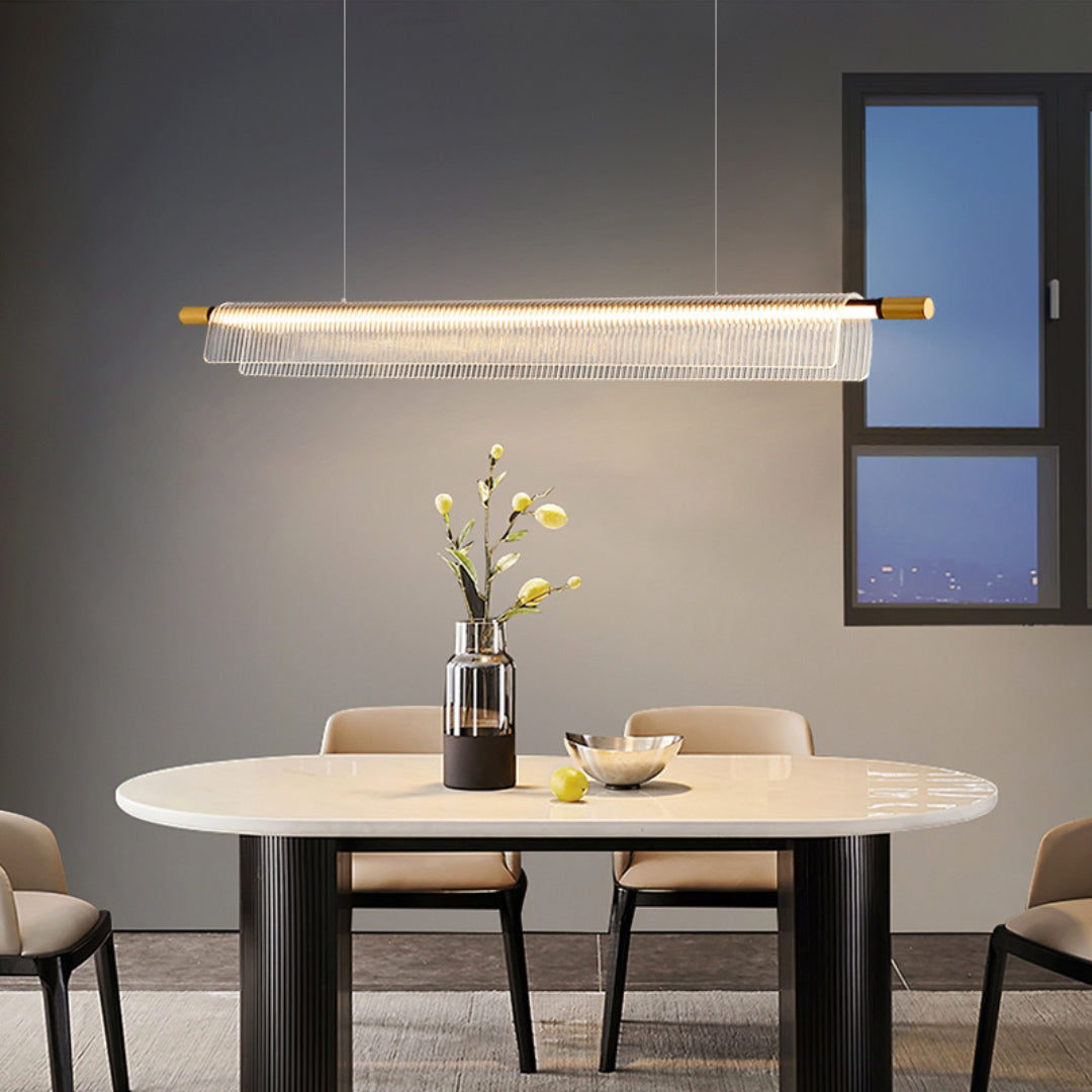 Illuminated clear ribbed linear pendant above an oval dining table and pale chairs near a dark-framed window