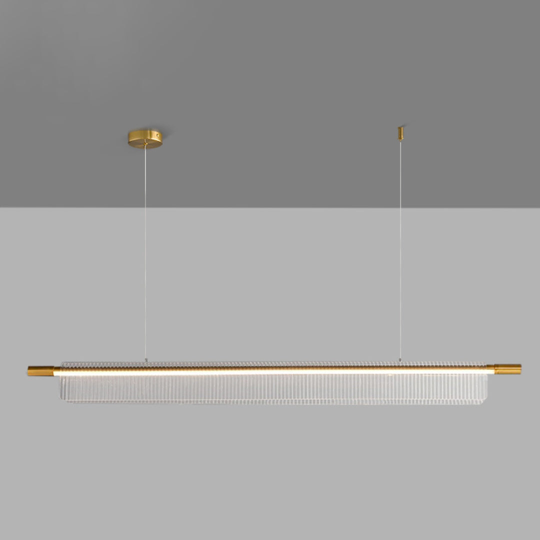 Front view of a long gold-tone linear pendant with clear ribbed acrylic and two suspension lines on gray