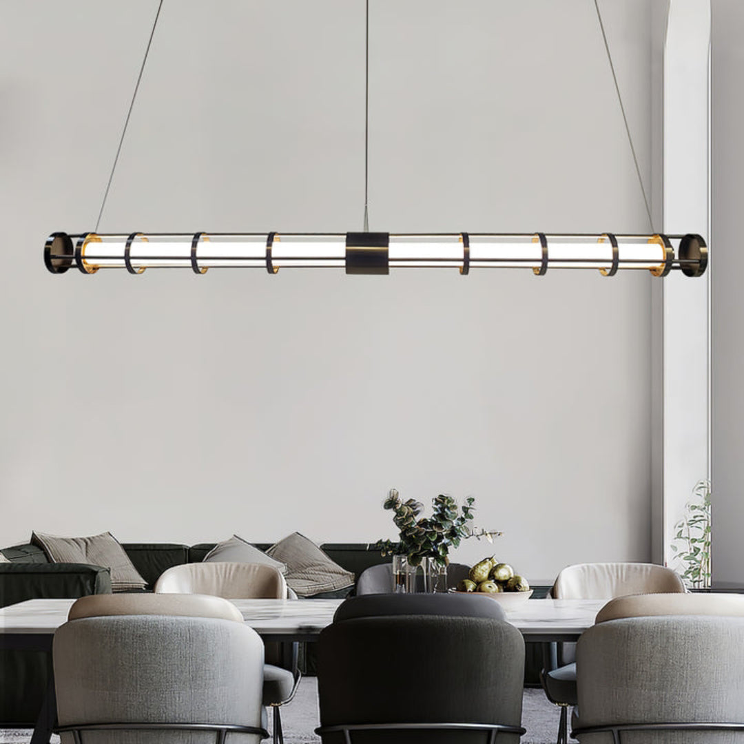 Black linear tube pendant above a pale veined dining table and gray chairs with a dark sofa beyond