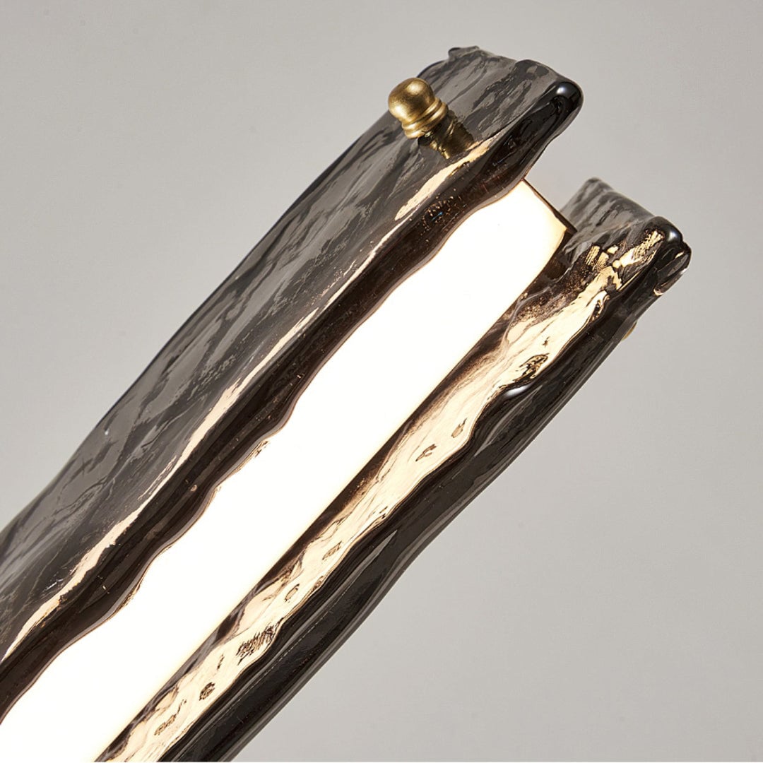 Underside close-up of illuminated strip between textured glass panels, with gold-toned end fixing