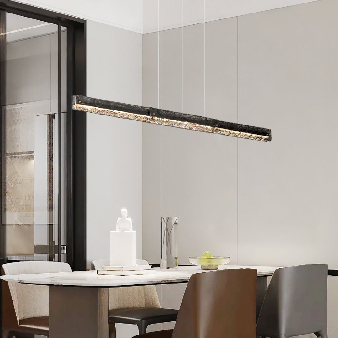 Dark-framed textured-glass pendant above a pale dining table with sculpture, tall vase and mixed chairs