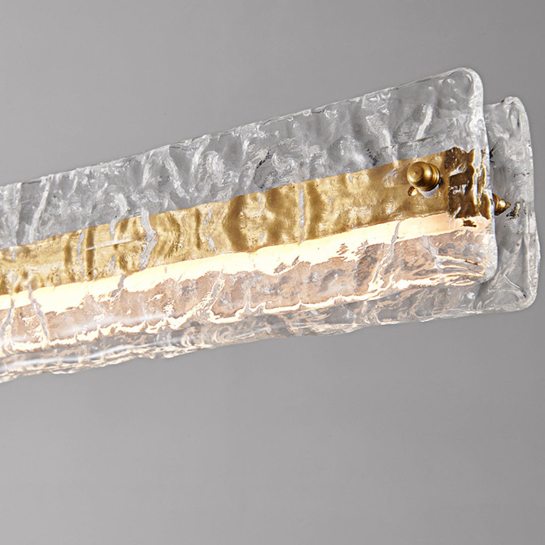 Close-up of clear textured glass, gold-toned centre strip, domed fixing and illuminated lower section