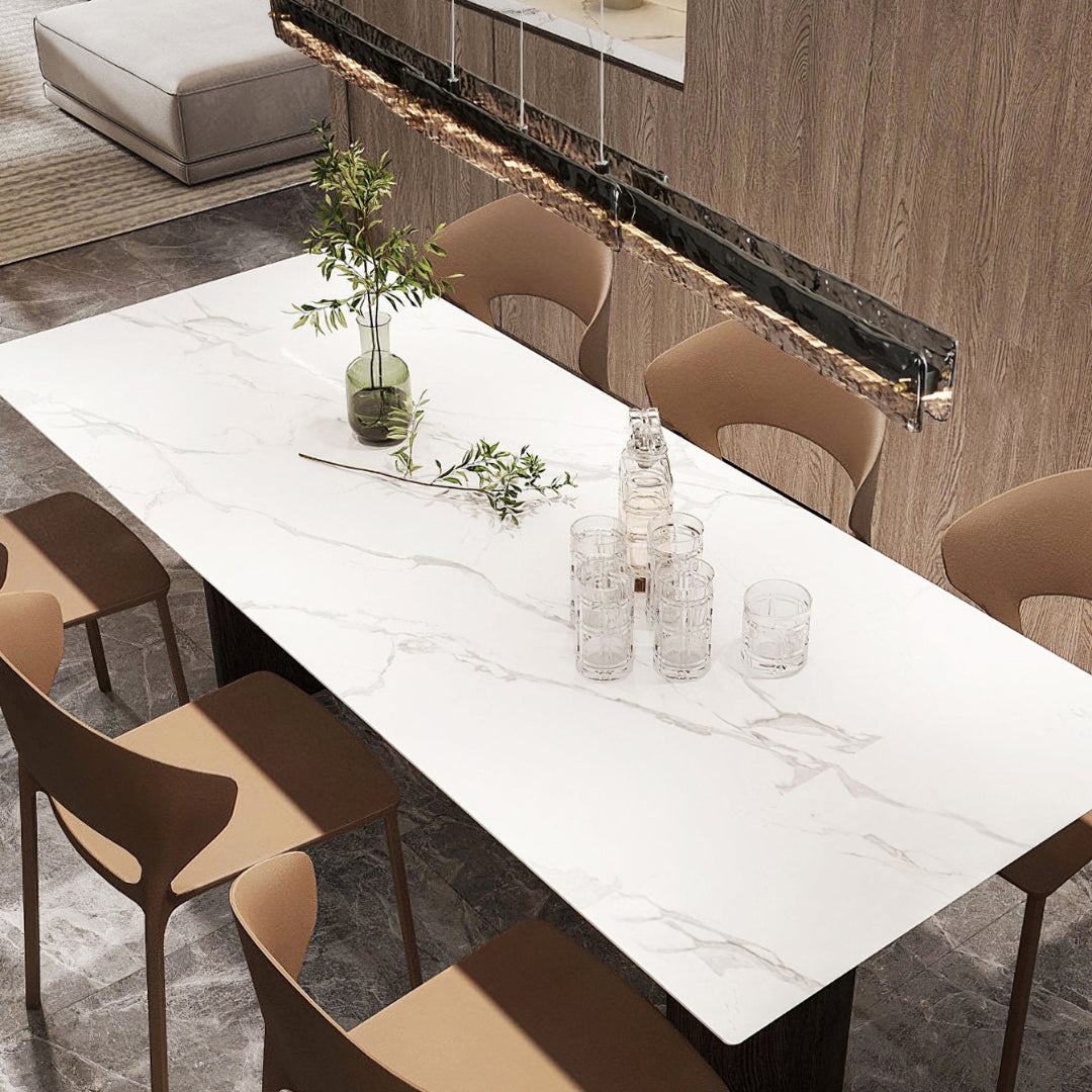 High-angle view of dark-framed linear pendant over a white dining table with brown chairs, bottle and glasses
