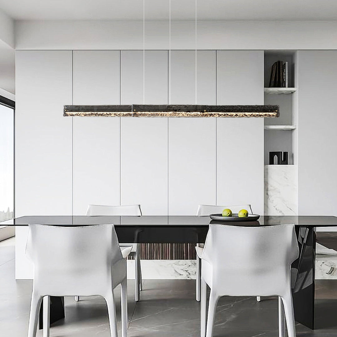 Front view of dark-framed glass pendant over a dark table with white chairs, fruit bowl and recessed shelves