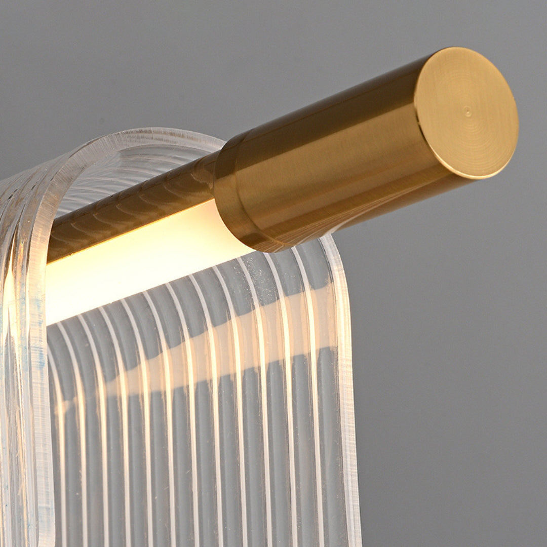 Close-up of a gold-tone cylindrical end and light strip beside curved clear ribbed acrylic