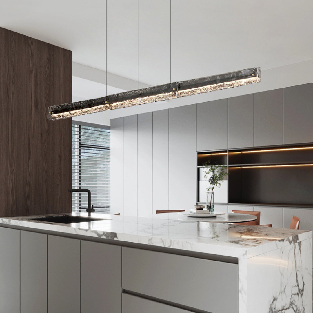 Capuccio Black + Clear pendant above a pale kitchen island with sink, stools and white cabinets
