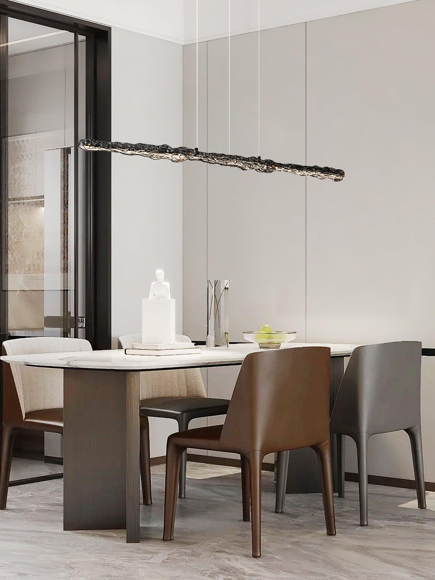 Dark wavy pendant above a pale dining table, books and a glass vessel beside black-framed glazing