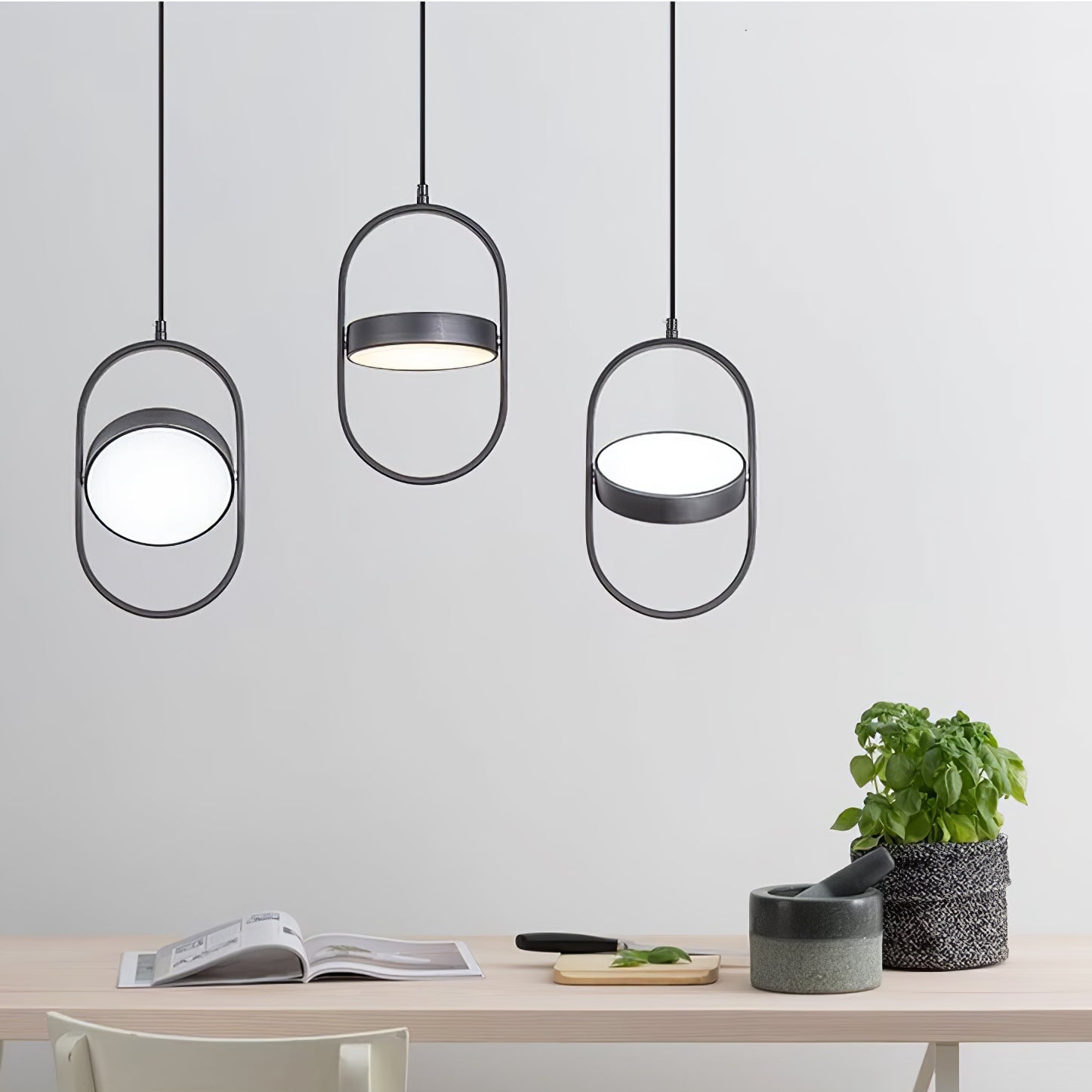 Three black oval KUU pendants with discs at different angles above a cabinet