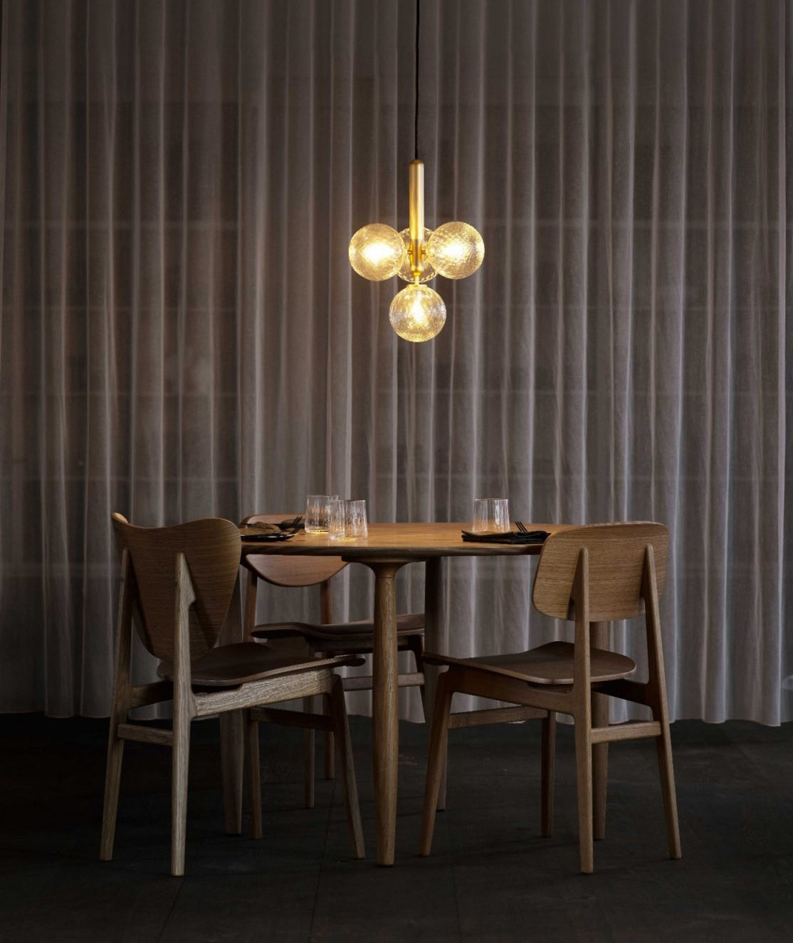 Warm-lit clear globes above a dark dining table