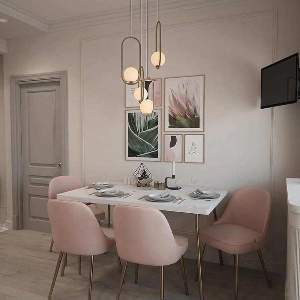 Three oval frame globe pendants above a dining table with pink chairs