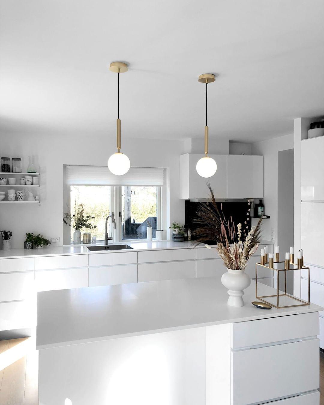 Two white globes with brass supports in a kitchen