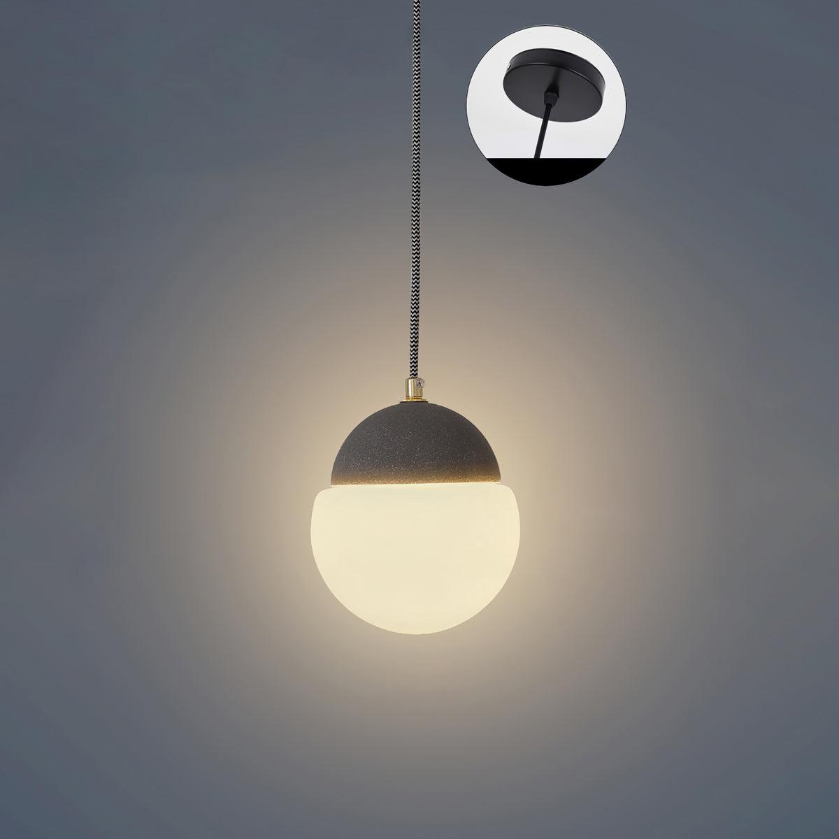 Cement Eclipse pendant light with a black cap and illuminated white globe