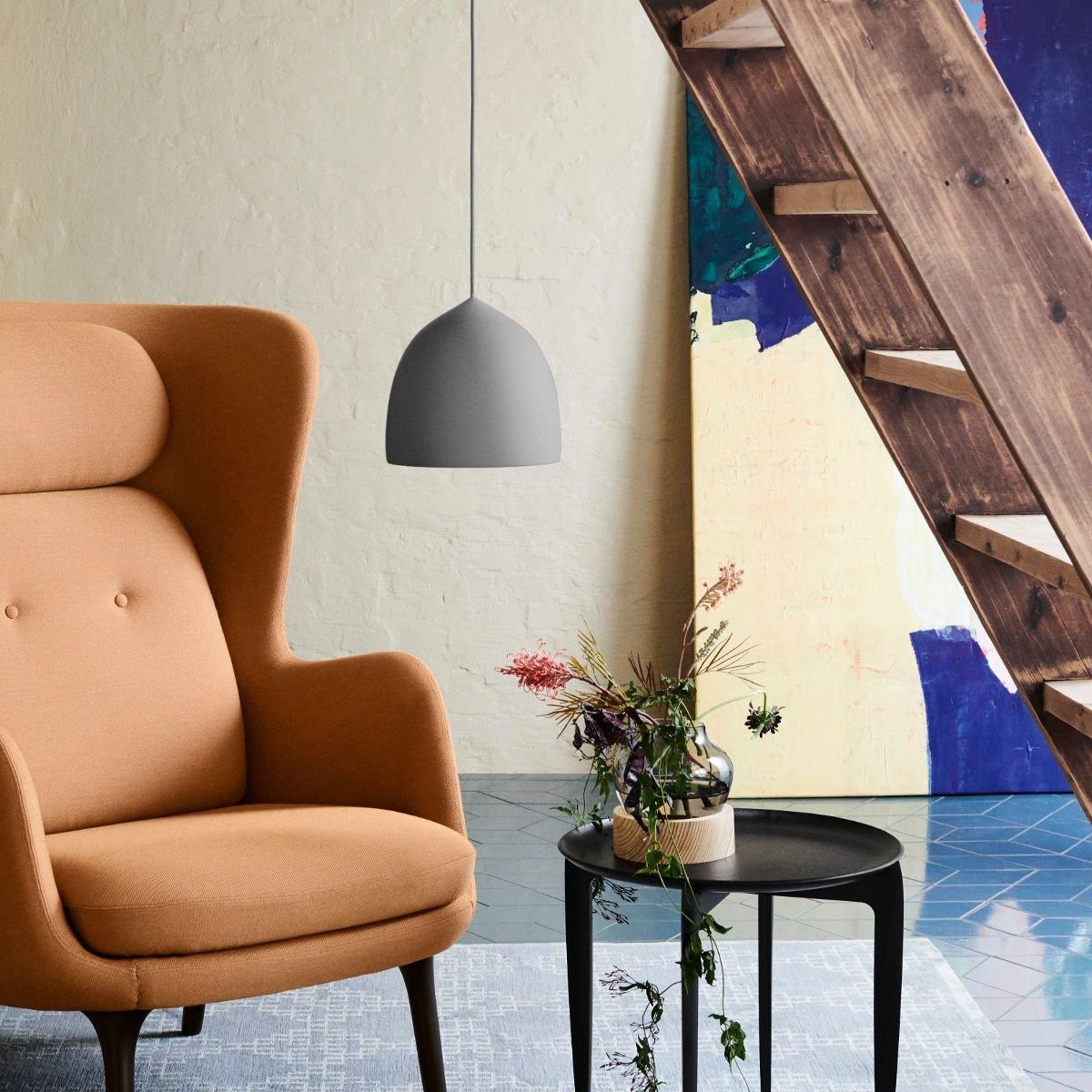 Grey bell pendant beside a staircase and orange chair