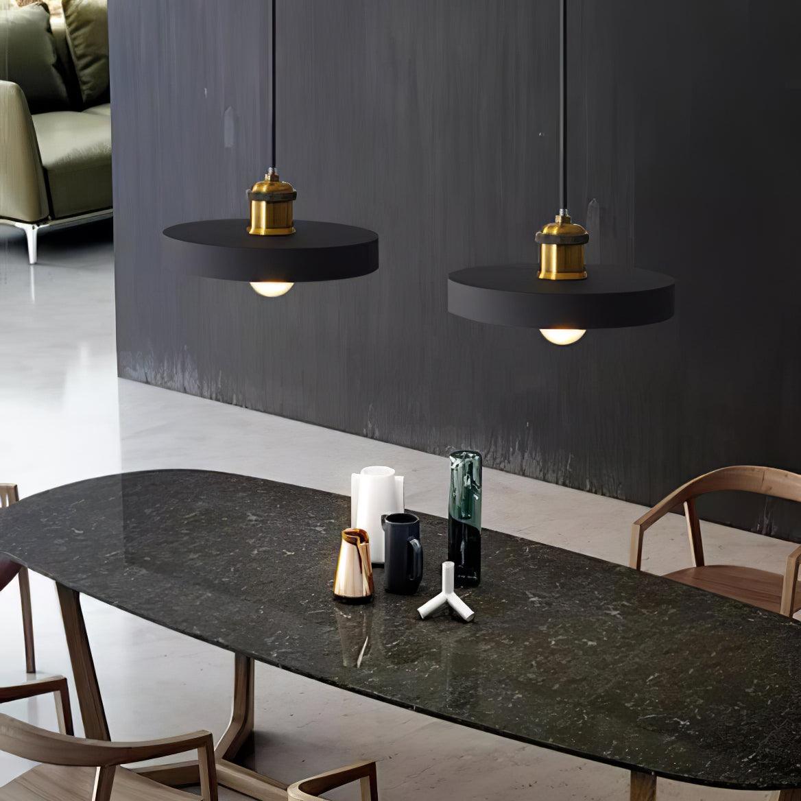Two black shallow disc pendants above a dark dining table
