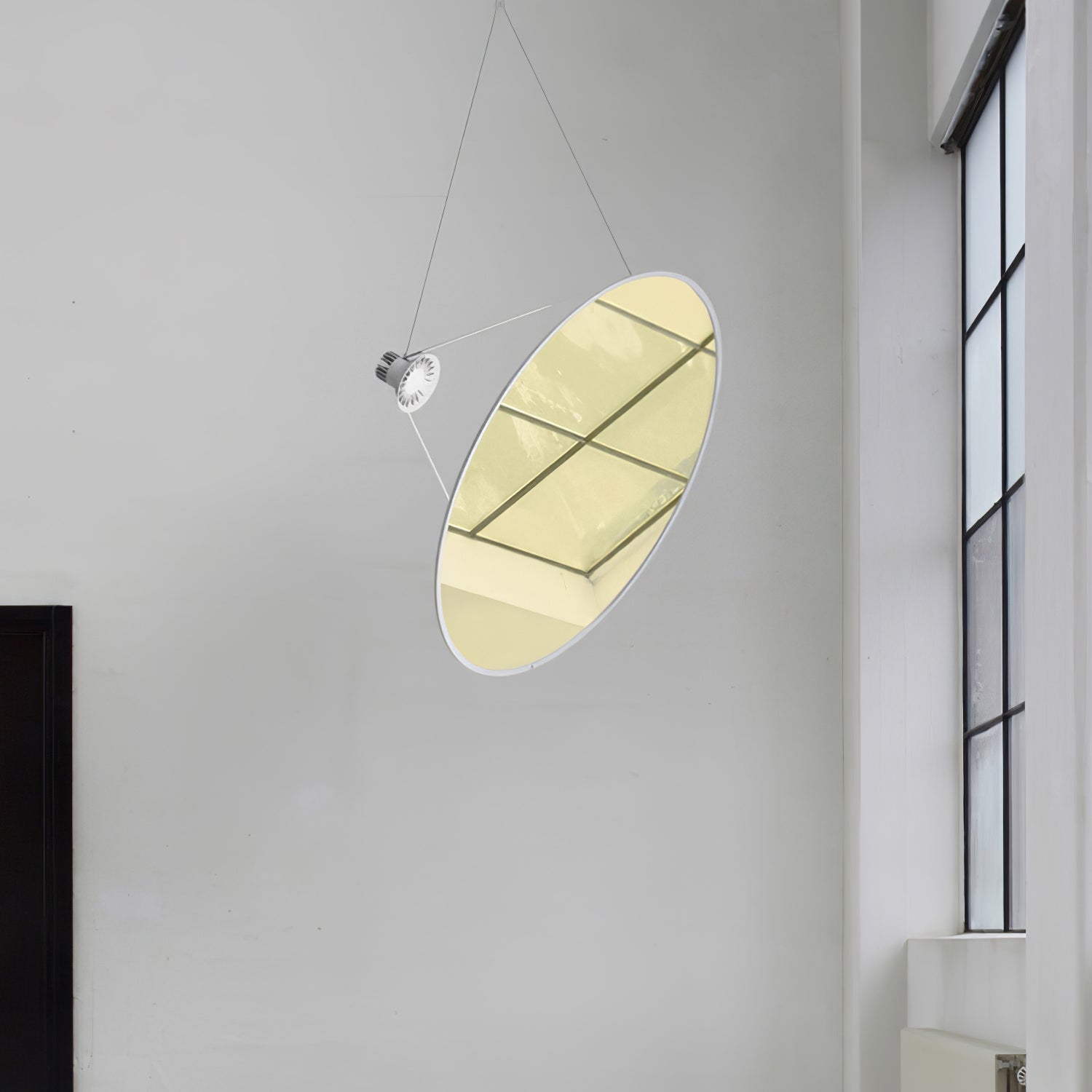 Gold-toned reflective disc and silver-coloured light head near a tall window